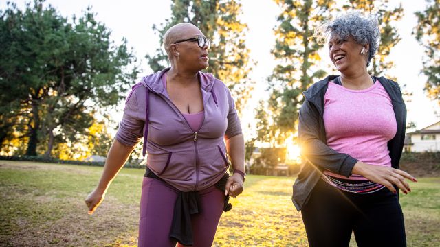 Two older women in pink taking a morning walk together in the park.