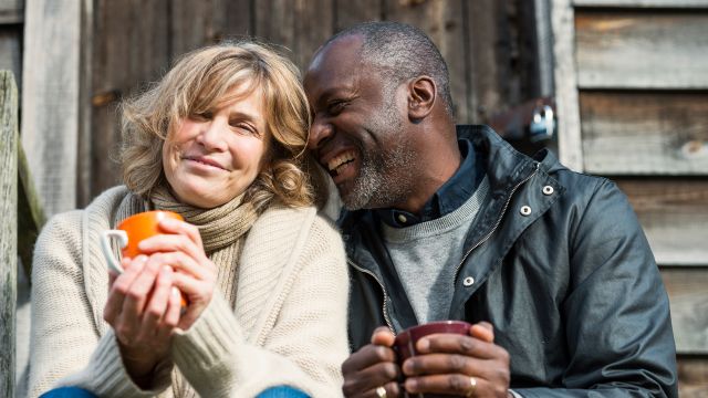 An older couple enjoys time together while drinking mugs of coffee. Being supportive to a partner with ovarian cancer can be challenging, but there are resources that can help.