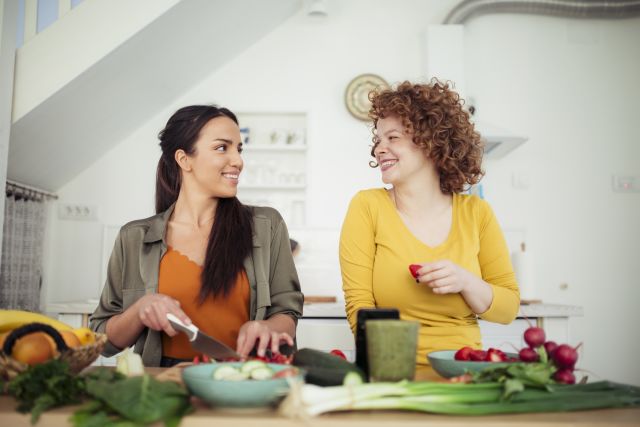 two women in kitchen prepare a healthy meal with fruits and vegetables