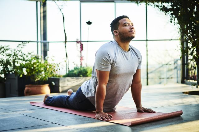 Black man does yoga in a sunny room