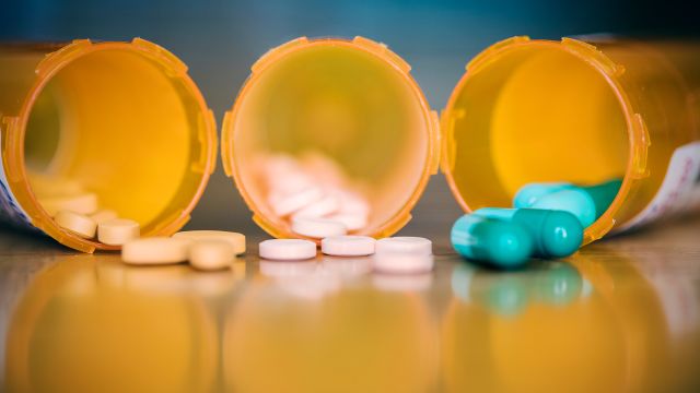 Pills spilling out of prescription bottles on a table. 