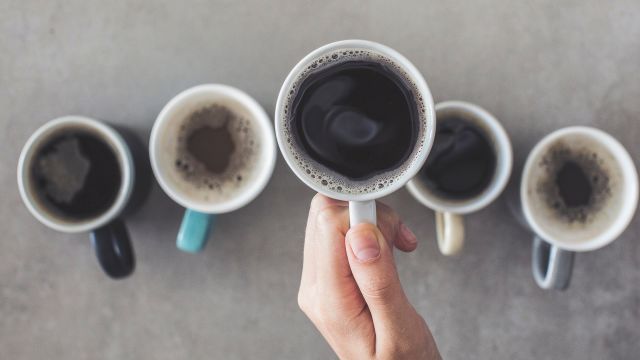 Multiple cups of coffee sit on a table.