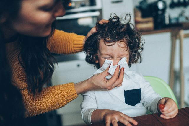 Parent helping a child blow their nose