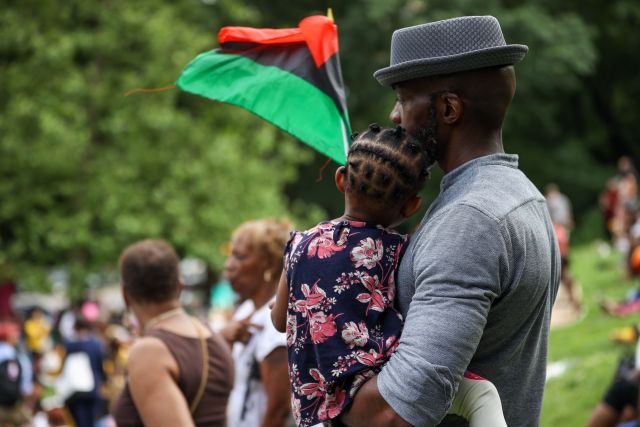 A Black man holds his daughter during an observance of the Juneteenth national holiday