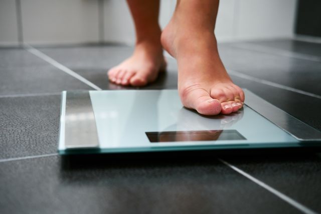 Two bare feet stepping onto a scale