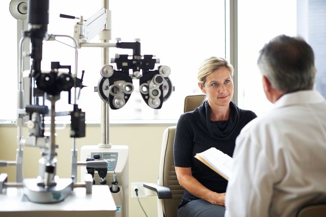 a middle aged blonde woman speaks to an ophthalmologist at an eye appointment