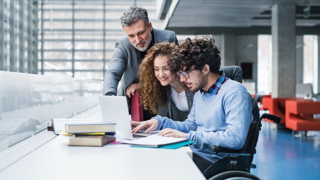 A young college student with spinal muscular atrophy works with a professor and a fellow student.