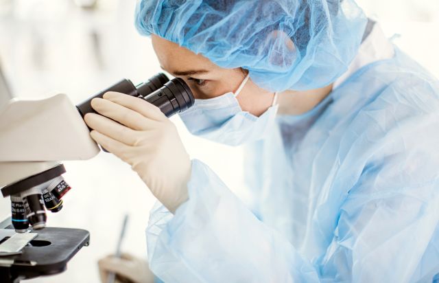 a scientist looking into microscope