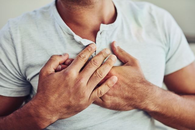 A young man experiencing chest pain places his hands on his chest