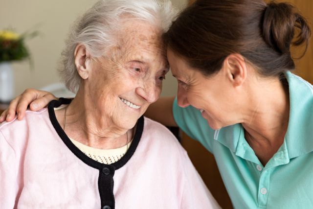 older woman with dementia being comforted by caregiver