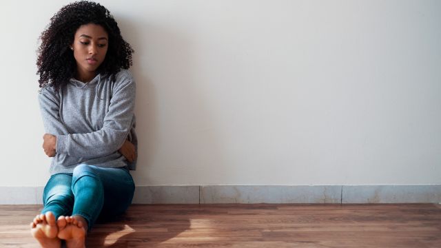 A young woman sits against the wall, exhausted.