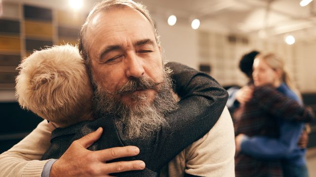 A man and woman hug at a support group meeting. Support groups can be helpful for both cancer patients and caregivers.