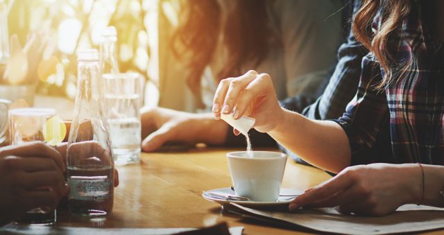 woman using artificial sweetener in coffee