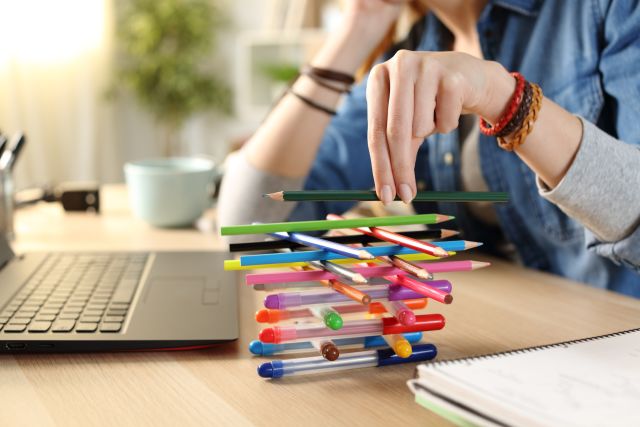 hand of bored and distracted person with adhd stacking pencils