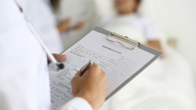 Female medicine doctor filling in patient medical history list during ward round. Medical care or insurance concept. Physician ready to examine patient and help