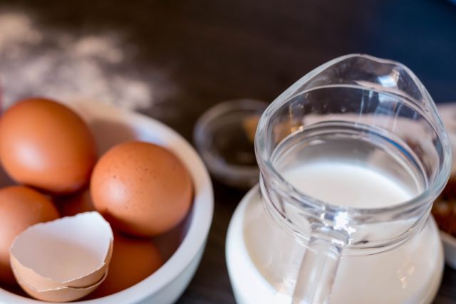 Closeup of eggs in a bowl and milk in a glass pitcher on a table