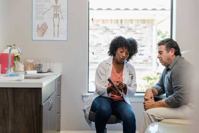 healthcare provider explaining something to patient on tablet