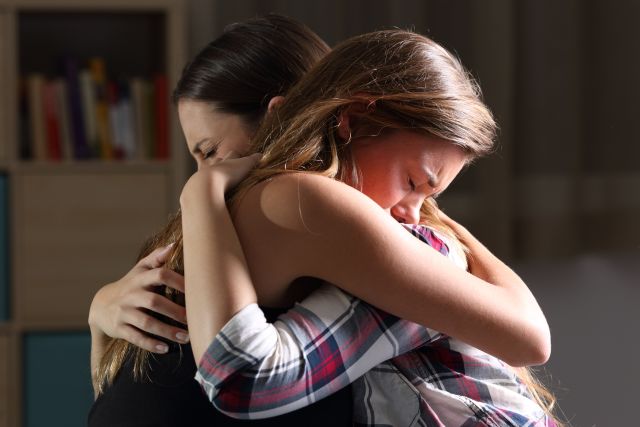 two young women embrace in grief