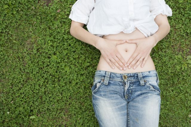 Woman with Crohn's lying on the grass with her belly exposed