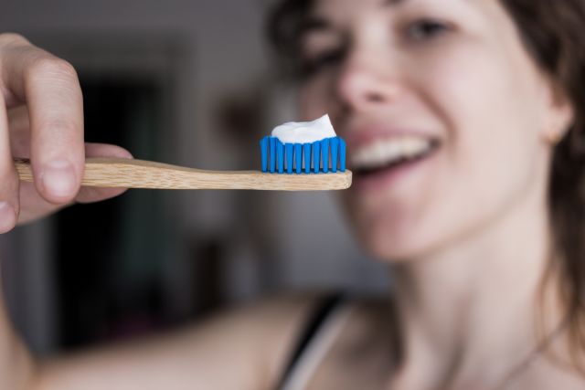 woman holding up a toothbrush with toothpaste 