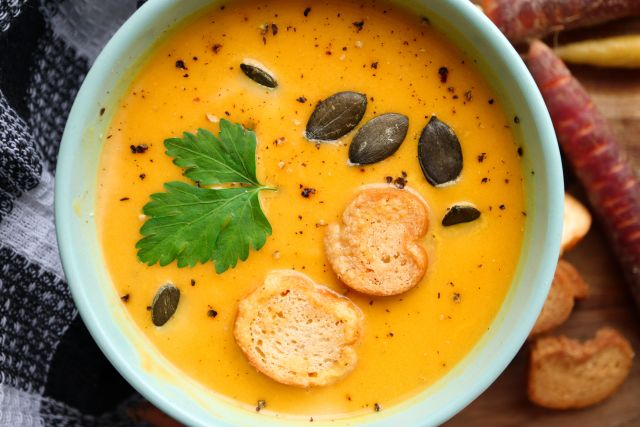 closeup of warm bowl of pumpkin soup garnished with seeds