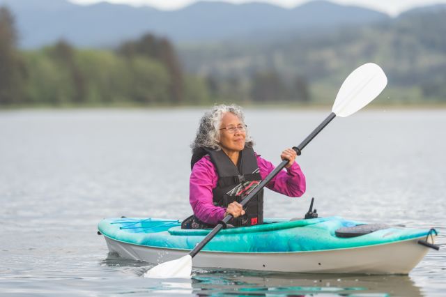 Vibrant senior woman enjoys a beautiful Oregon evening kayaking on the coast