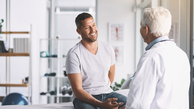 senior doctor giving his smiling male patient a thorough checkup during his consultation