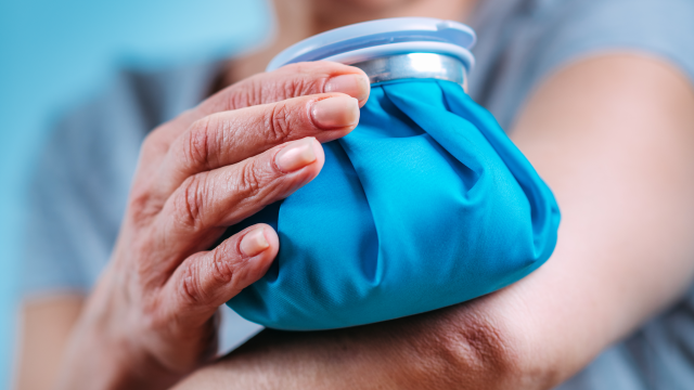 woman putting an ice pack on her elbow to treat Rheumatoid Arthritis Pain