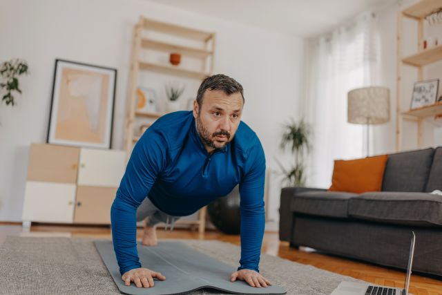 man doing yoga on a mat in his living room for weight loss