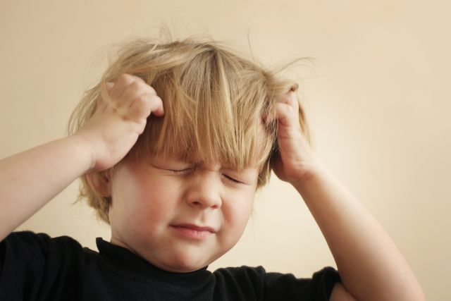 Blond child scratching head with both hands