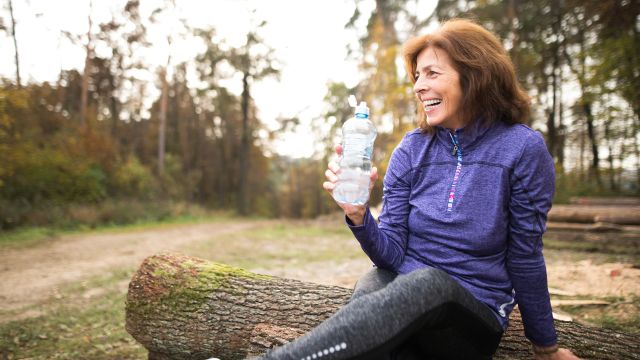 Senior woman outside after workout holding water bottle.