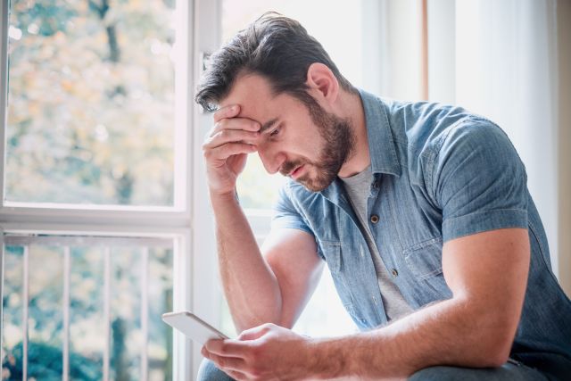 adult man looking troubled while reading news on a tablet