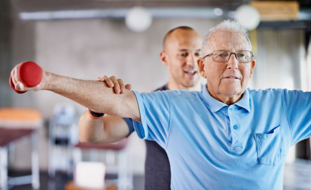 an older white male adult man participates in physical rehabilitation after experiencing strokes related to vascular parkinsonism