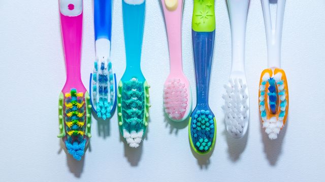 Colorful toothbrushes on pale background.