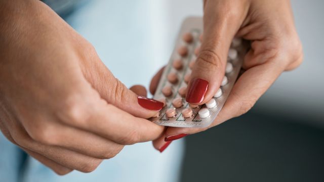 A woman taking a birth control pill out of the pack.