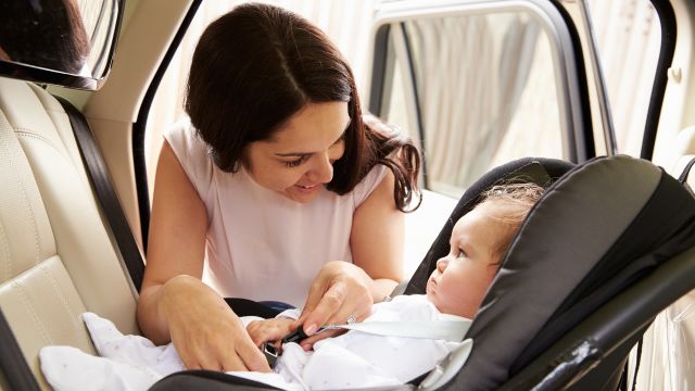 Mother putting their child into a carseat.