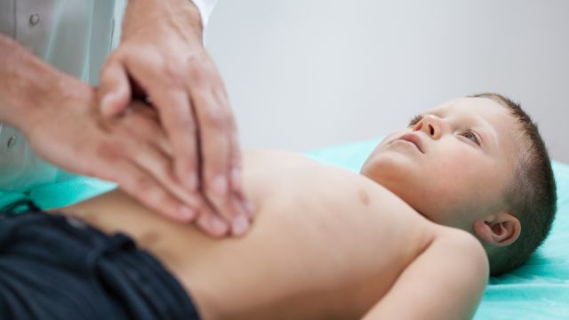 A doctor pushing on a boy's stomach to see where the pain is originating from.