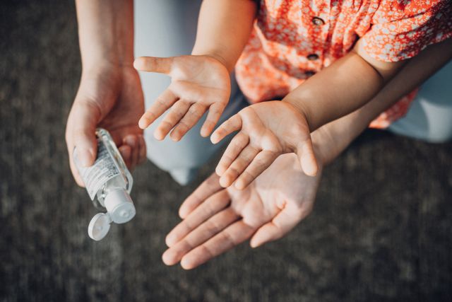 parent squirting hand sanitizer on child's hands