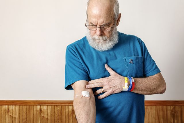 A senior man with a cotton ball bandaged to his arm after a blood test. A blood test can determine if a person can be treated with immunotherapy for metastatic uveal melanoma.