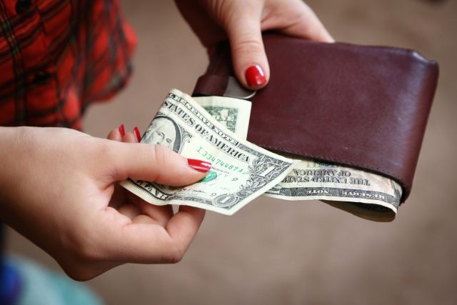 woman taking one dollar bill out of wallet