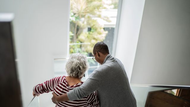 A senior woman has difficulty walking down stairs as her medication for Parkinson's disease begins to wear off.