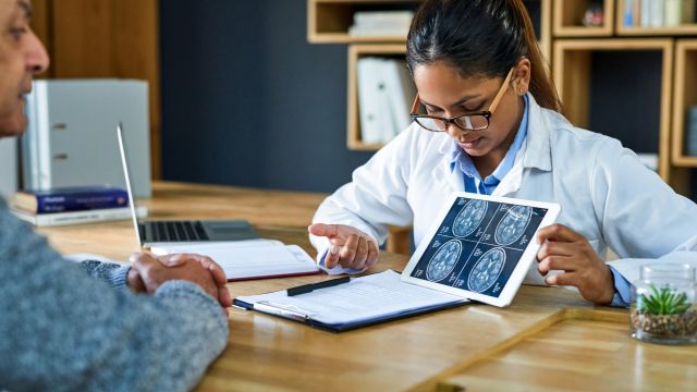 A neurologist explains test results to a patient with Parkinson's disease.