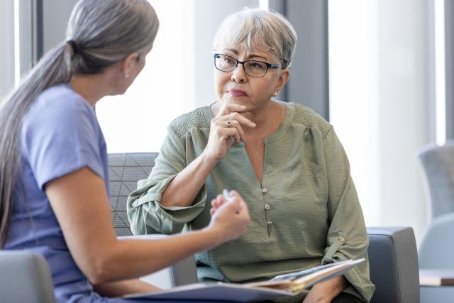 Middle aged Latina woman listens carefully as she receives information about cancer immunotherapy options from her healthcare provider.