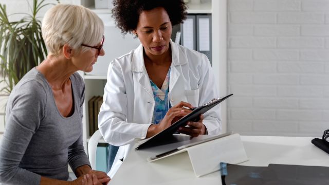 A senior woman speaks with her hematologist about the results of blood tests.