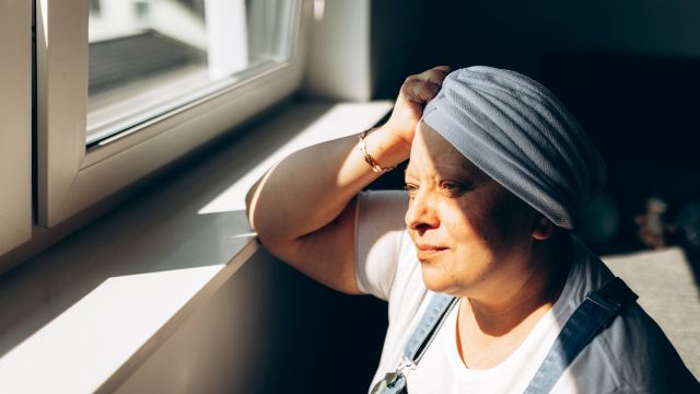 Woman with cancer looking out of a bright window before chemotherapy treatment