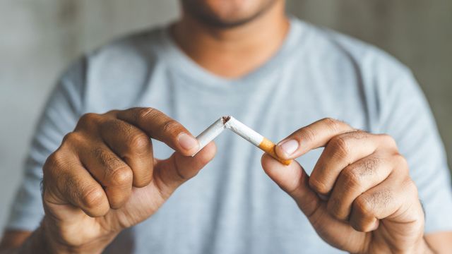 Man with lung cancer breaking a cigarette to quit smoking
