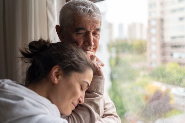 adult female embraces older male, puts her head on his shoulder