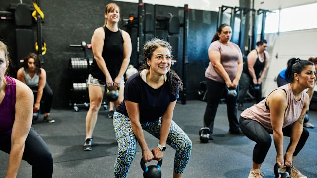 A group of women use kettlebells during a fitness class. Weight-bearing exercises can have multiple benefits for women during menopause, including improving bone density.