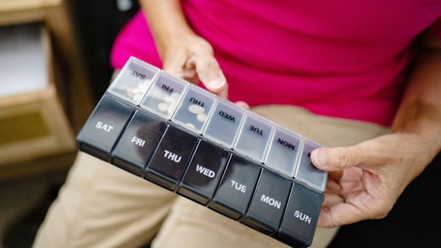 A woman checks her pill organizer. Strategies like pill organizers and reminders are important when taking multiple medications with different dosing instructions.