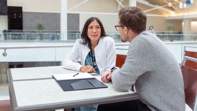 A male patient talks to a neurologist in the waiting area of a hospital. People with CIDP often need to work with a number of healthcare providers, and should take steps to coordinate care between their different healthcare providers.